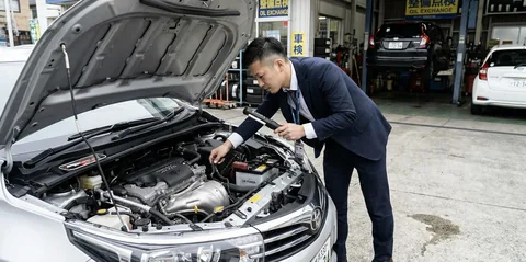 査定士がエンジンルームをライトで詳細検査しているシーン